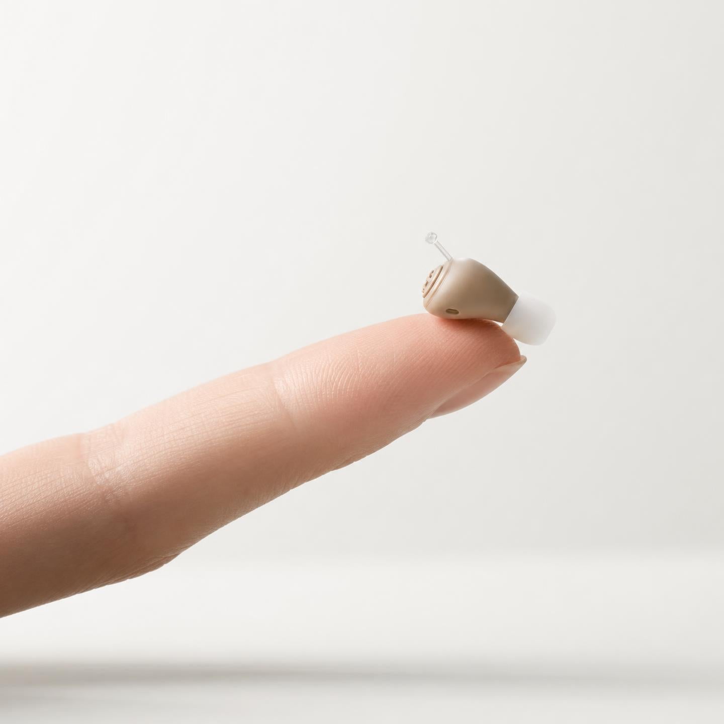 Tiny Boreal Comfort hearing aid resting on a fingertip